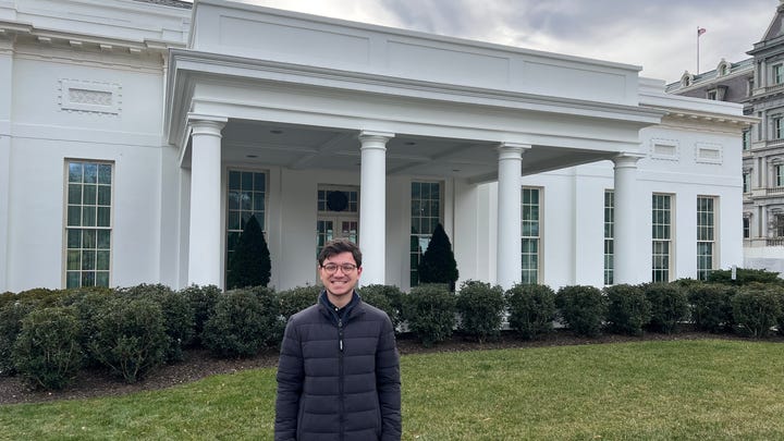 The first U.S. Digital Service intern, Sam, is standing in front of a U.S. government building.