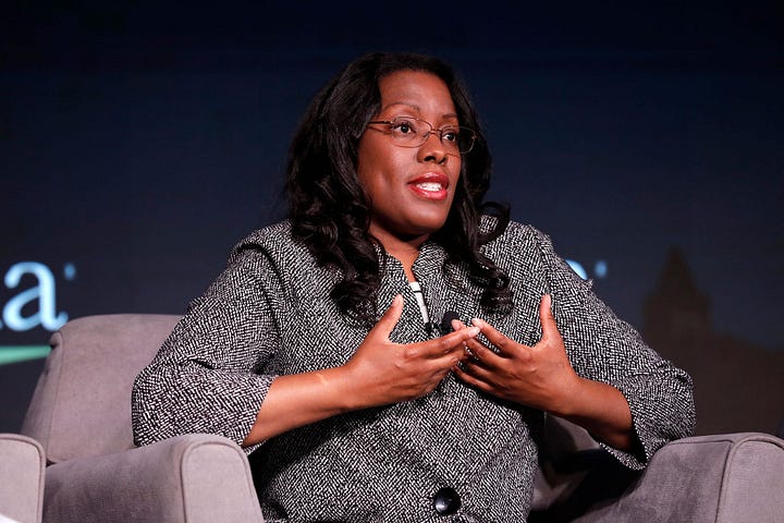 A Black woman speaking at a conference, sitting in a chair, Dana Peterson