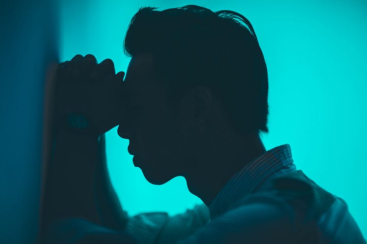 A frustrated man leaning against a wall