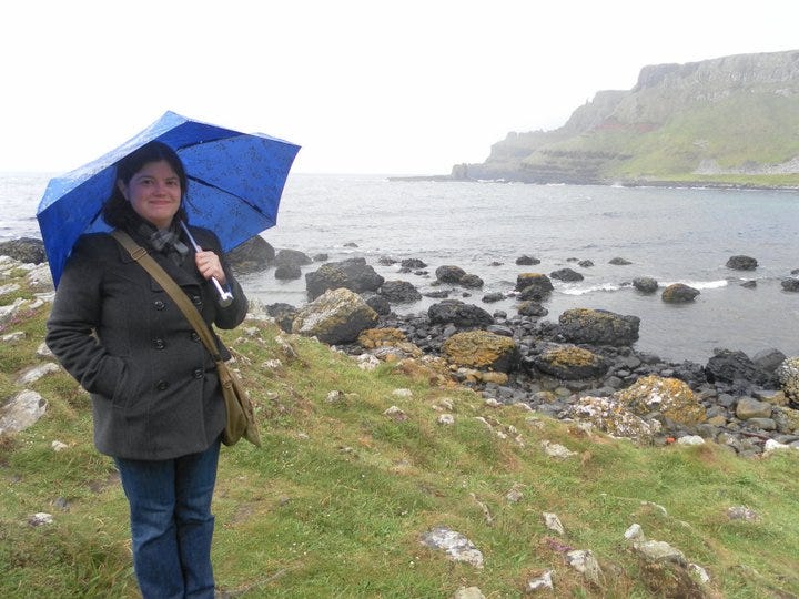 Image of a me with an umbrella standing along cliffs on the Irish coast
