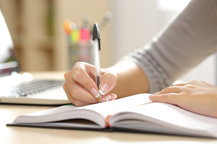 Student handwriting their schedule in an agenda at home