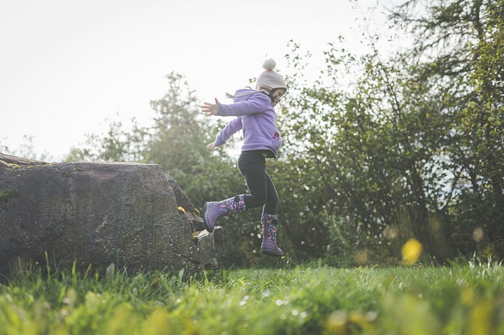 Child playing and jumping on grass