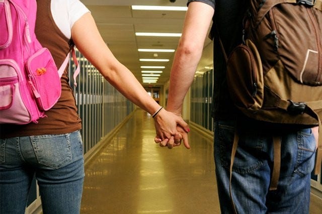 Teens holding hands in school