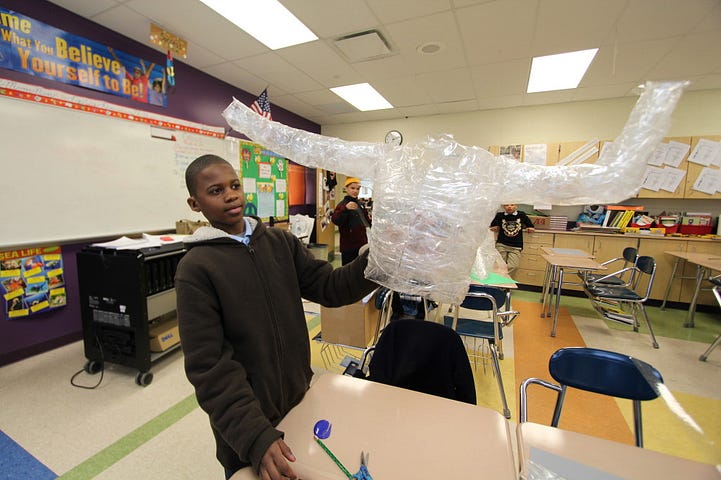 A student from Mound's 6th grade class with his team's in-progress torso casting.