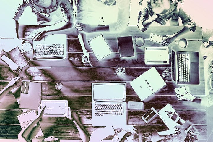 People sitting with laptops at a table.