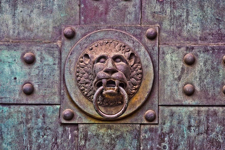 Old iron doorknocker: lion’s head with the ring in its mouth.