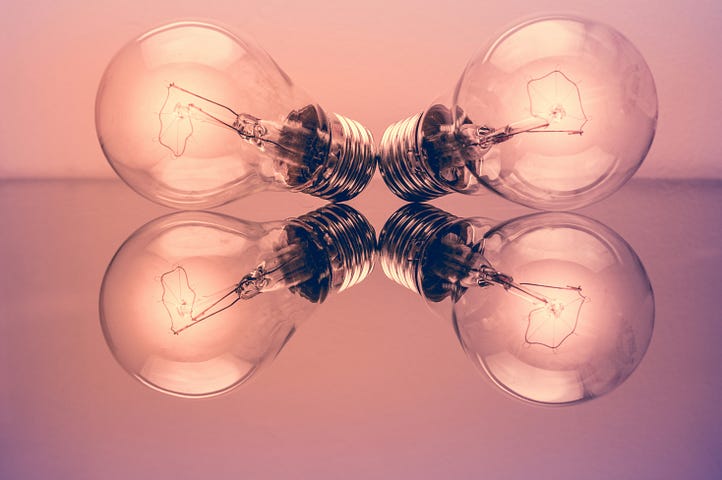 two lightbulbs on a reflective floor, giving the illusion of four lightbulbs