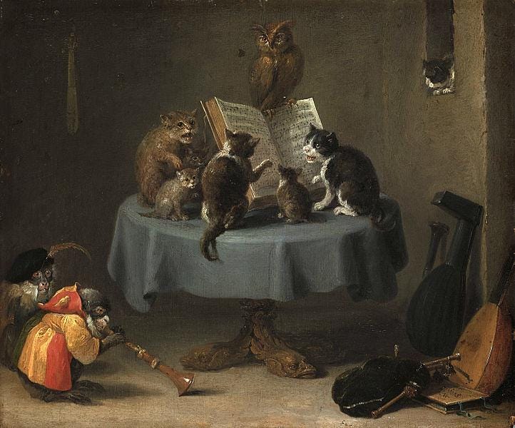 Cats sitting on a table in front of an open book of music. A cat in a colorful costume playing a baroque oboe or some such instrument. Cats, cats, cats.