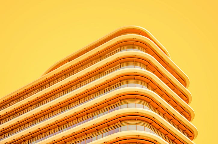 A yellow building with curved balconies, shown against a yellow sky