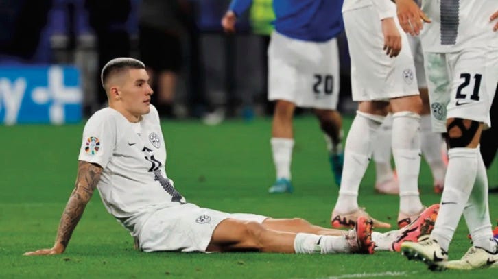 photo of sad Slovenia player sat on ground leaning back