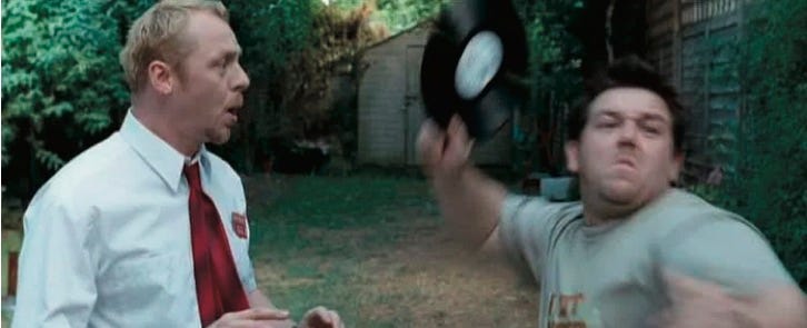 photo of man speaking to another man who is throwing vinyl record