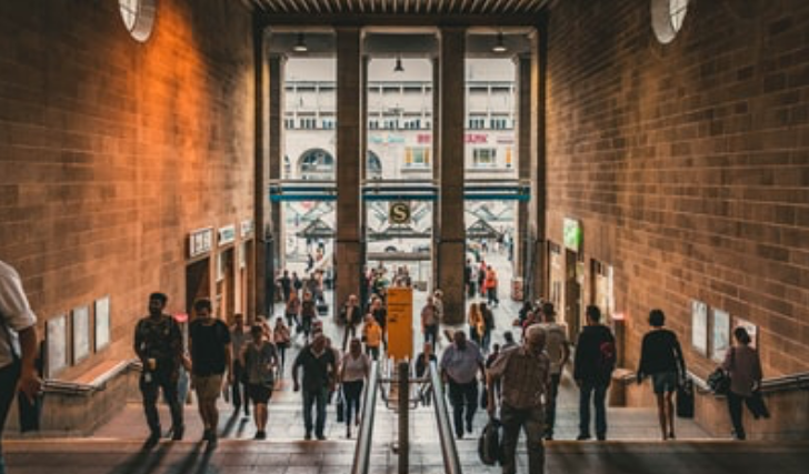 Várias pessoas entrando e saindo de um prédio.