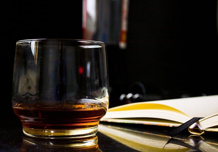 whiskey filled glass and book