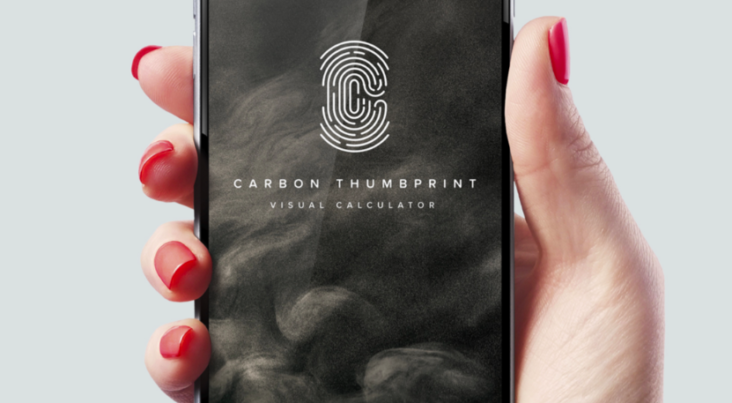 A hand holding a smart phone with the screen showing Belong’s Carbon Thumbprint app.