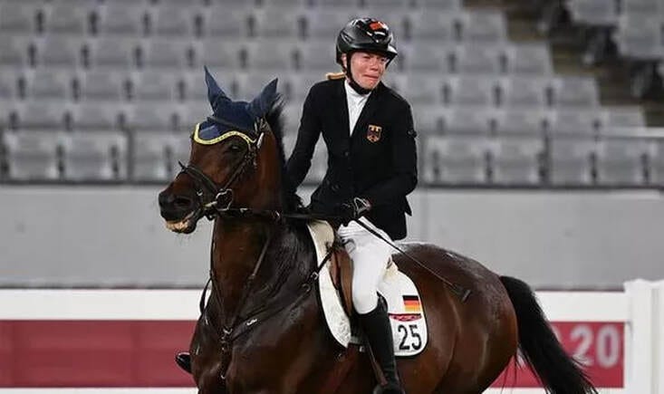 a woman cries while riding a horse in an arena
