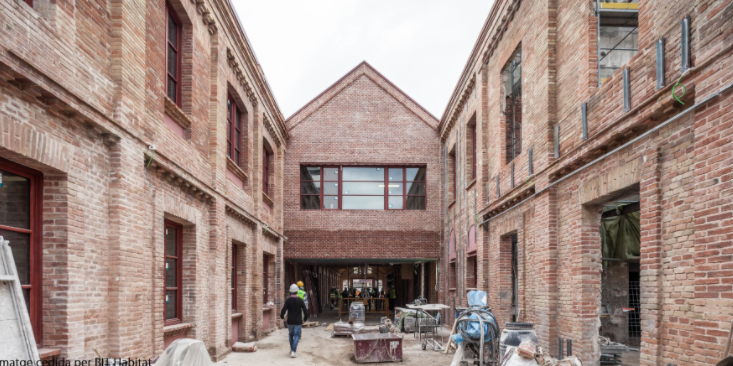 Old brick buildings in Barcelona on a construction site with two construction workers walking away