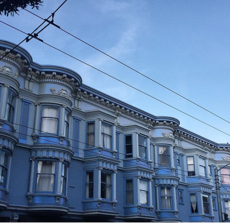 A row of houses in San Fransisco against a blue sky.