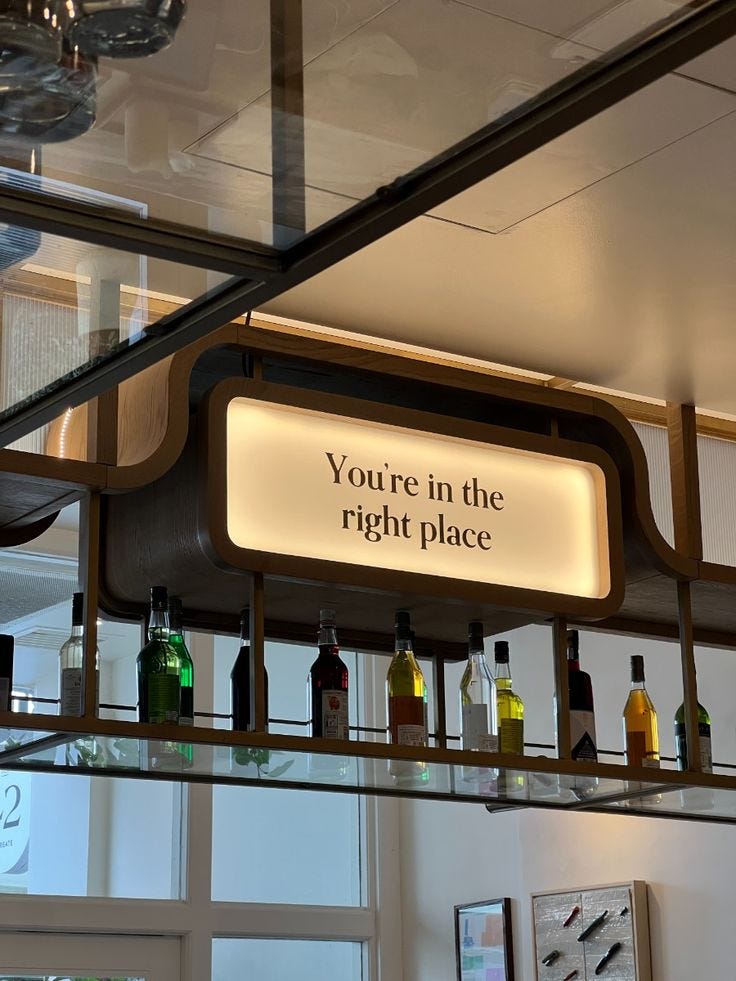 A neon sign above a wine bar with the words, “You’re in the right place”, written in black.