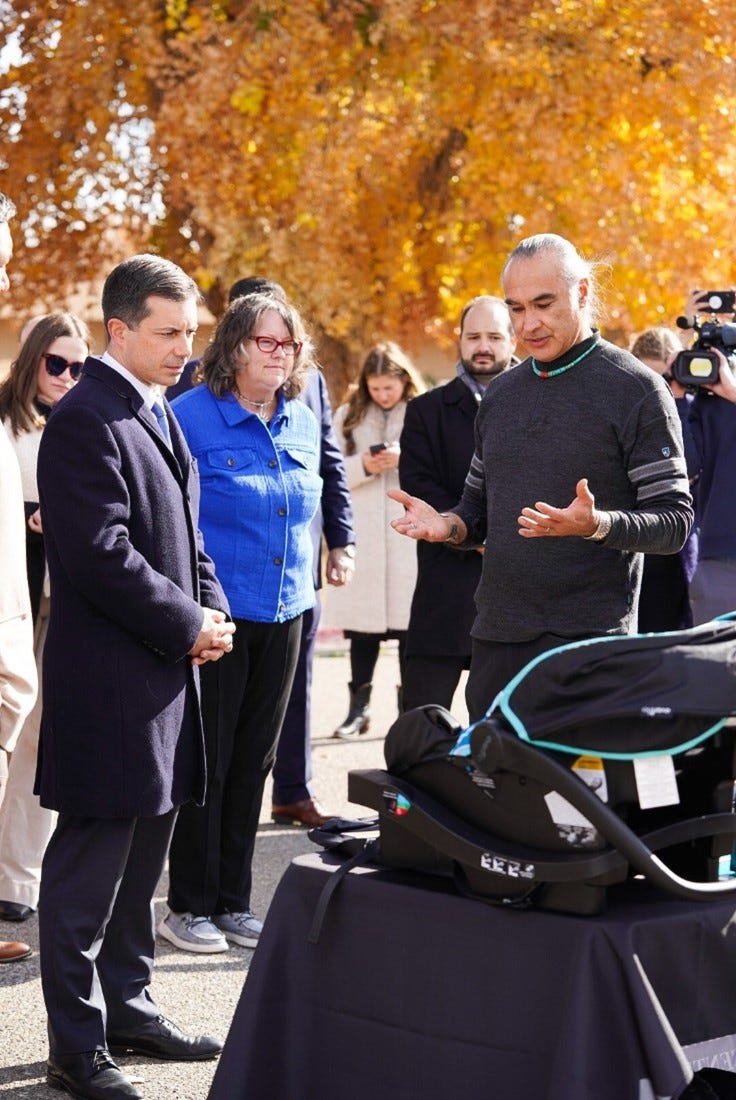 Secretary Buttigieg observes a car seat and listens to a discussion about car seat safety.