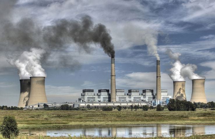 A landscape of a power plant in South Africa with various chimneys releasing smoke and steam