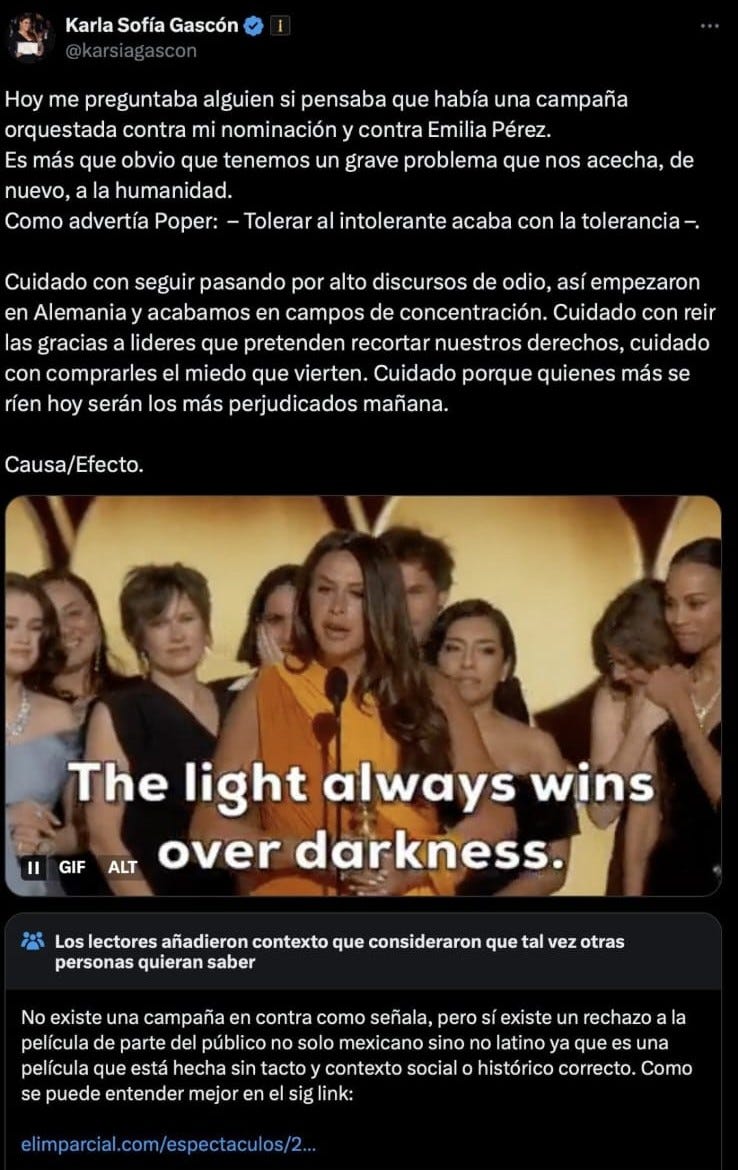 Screenshot of a tweet by Karla Sofía Gascón where, in Spanish, she wonders whether there’s a campaign against her nomination and Emilia Pérez. She warns about overlooking politicians flukes when they’re set on cutting back people’s rights, ending with a gif of herself at the Golden Globes stating: The light always wins over darkness. Below this, a community note clarifies that there is no actual campaign against her, just a general rejection from the Mexican and Latin American public.