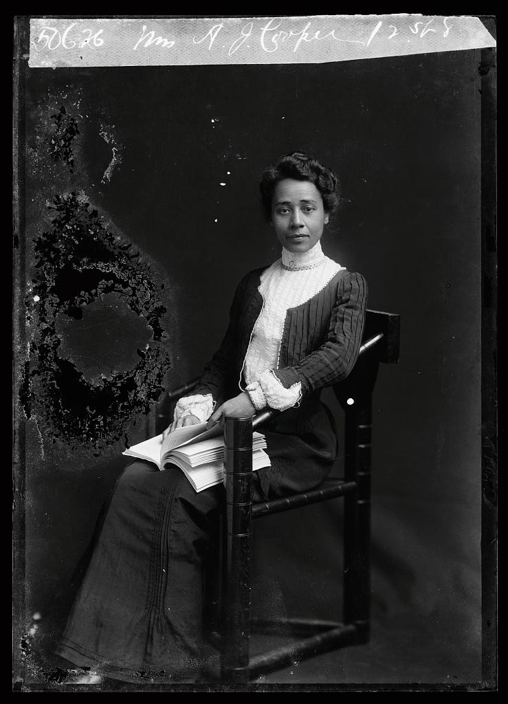 Medievalist, Anna Julia Cooper, sits in a chair with a book on her lap.