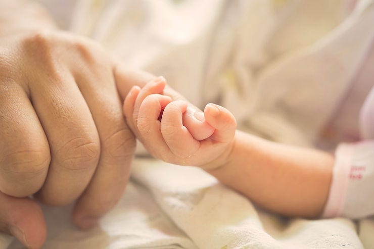 Baby holding parent’s hand