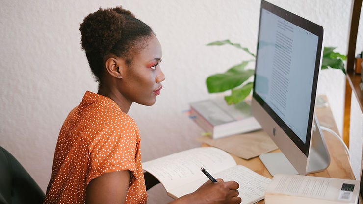 A student learning using her computer and notebook.