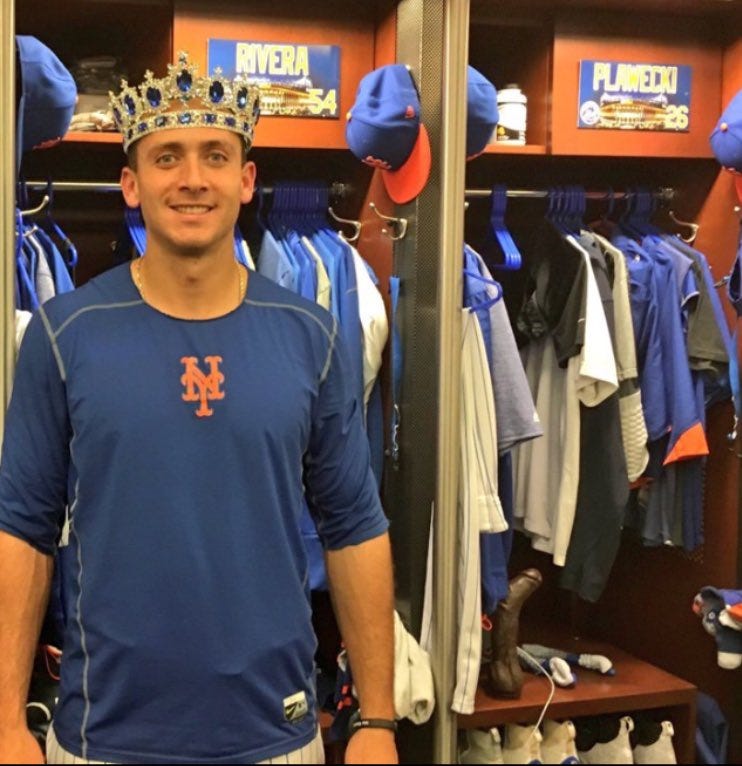 New York Mets infielder T.J. Rivera poses in front of catcher Kevin Plawecki’s locker where there is a visibly large dildo.