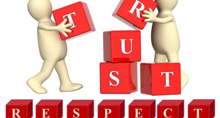 Two people are arranging and building the words TRUST and RESPECT from a blocks where there is written every letters of each words.