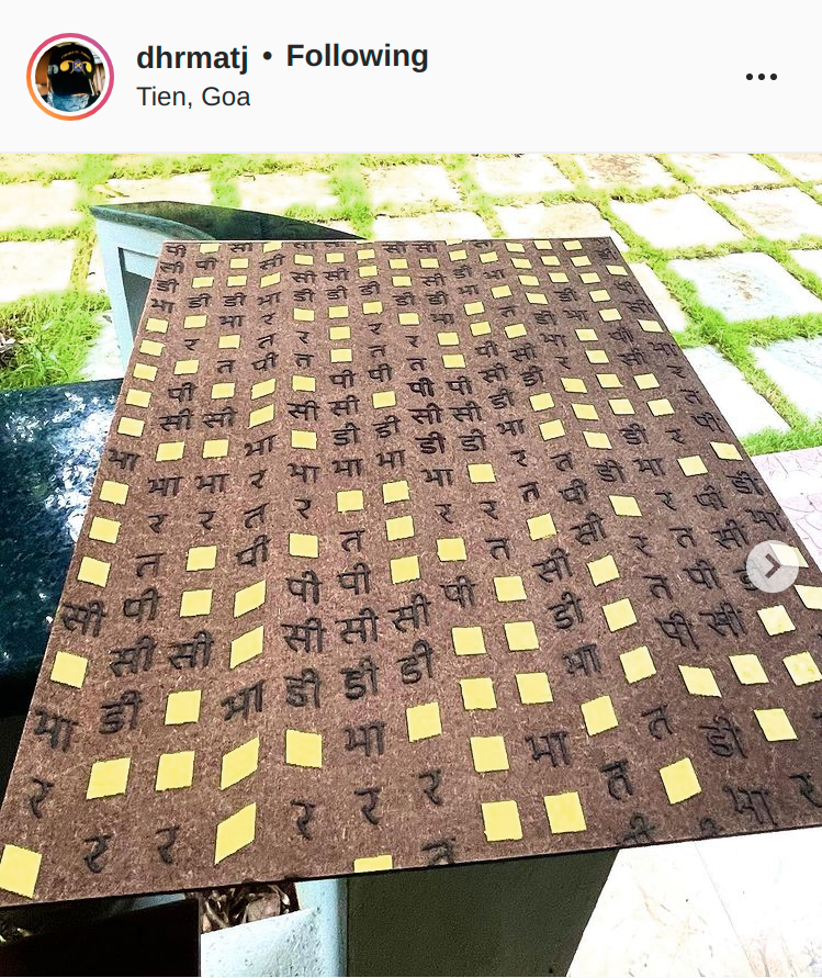 Screenshot of @dhrmatj’s Instagram post showing a photo of a wooden panel embossed and painted with a series of squares and symbols.