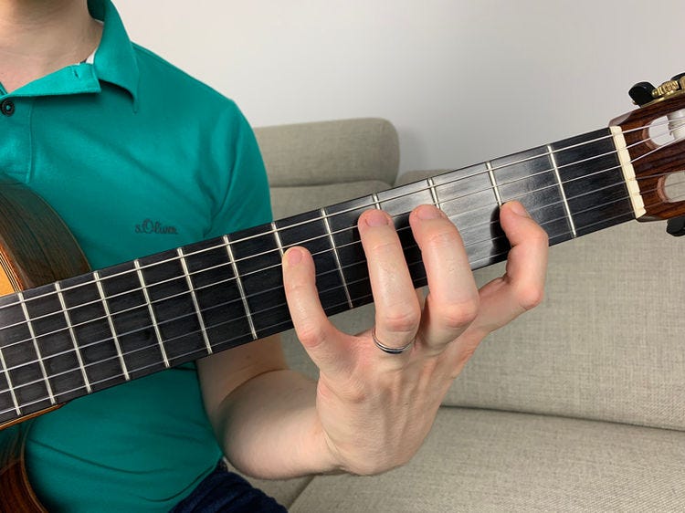 Fingers of the left hand on a guitar’s fingerboard