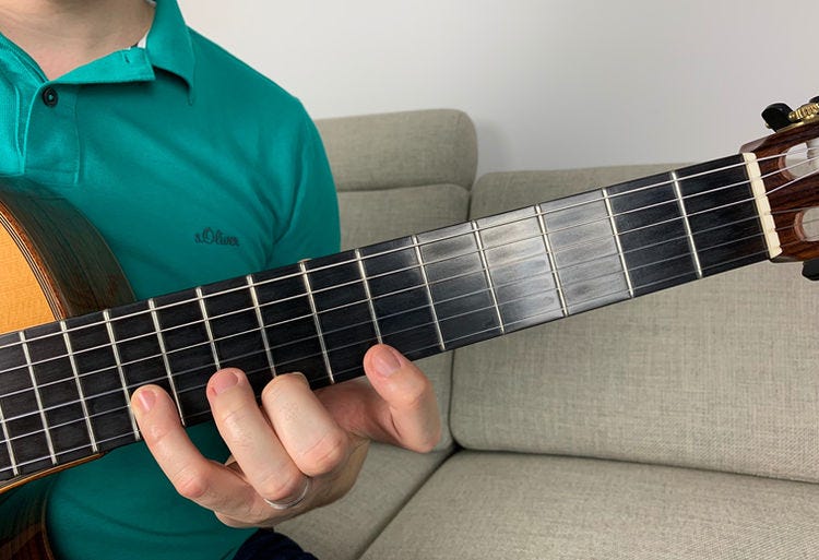 Fingers of the left hand on a guitar’s fingerboard