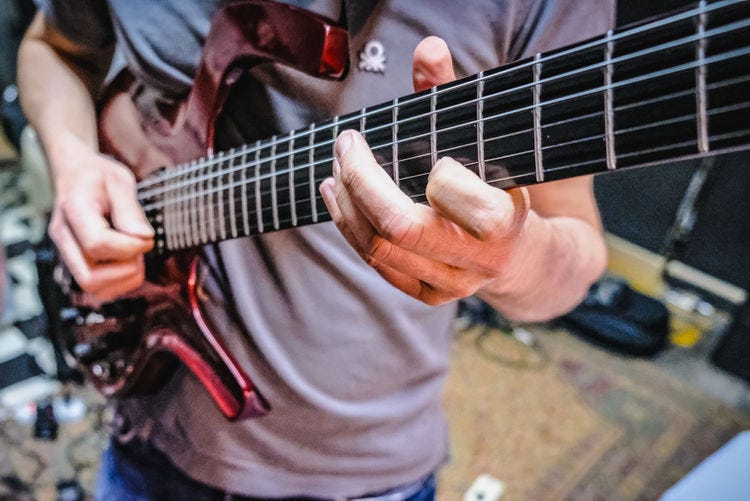 A man playing a red electric guitar