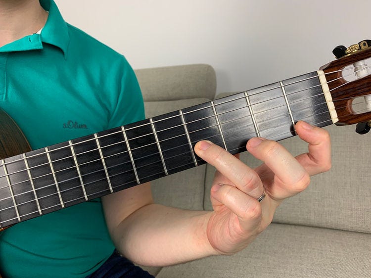 Fingers of the left hand on a guitar’s fingerboard