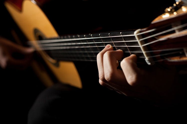 Guitarist’s left hand playing a chord on the fingerboard