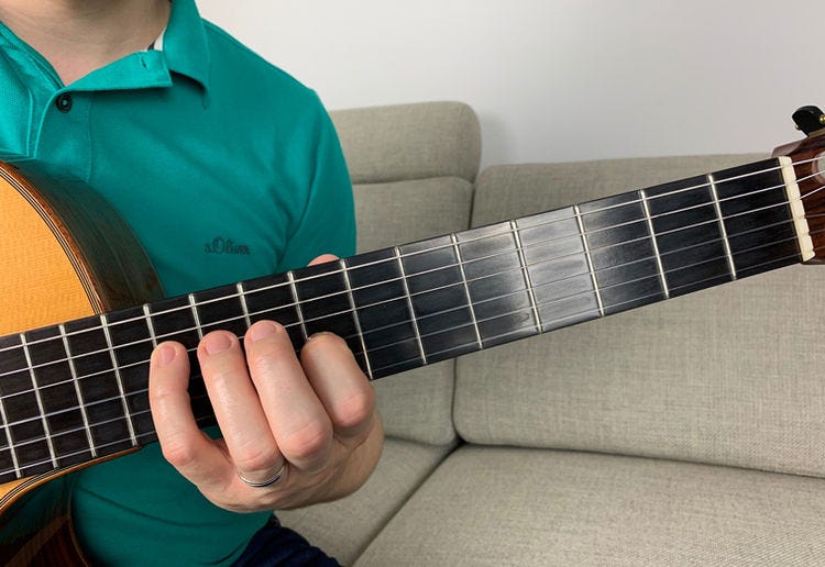 Fingers of the left hand on a guitar’s fingerboard