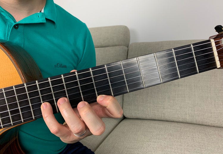 Fingers of the left hand on a guitar’s fingerboard