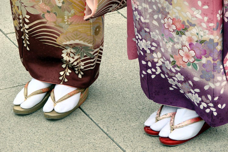 Duas mulheres de kimono calçando uma sandália tradicional