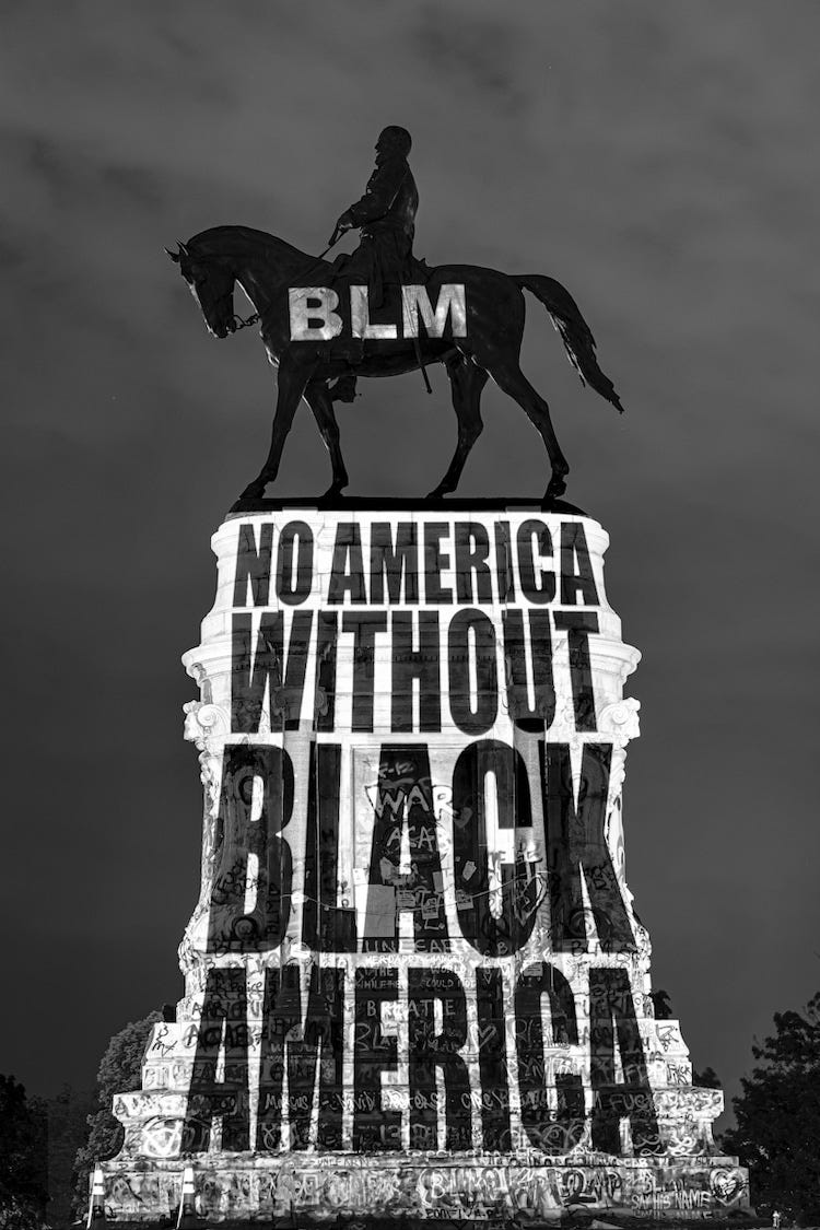 Photo of the former Robert E. Lee statue with a projection that reads: “No America Without Black America”