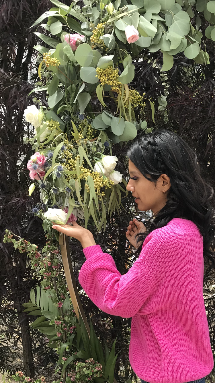 The author in a bright pin sweater look at a wilted rose.