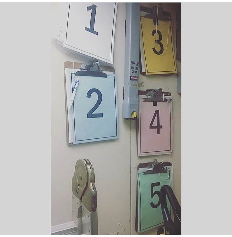a photo of numbers 1–5 , each on separate clipboards of different colors that are used in an emergency for ship drills and contain passenger lists and life raft numbers