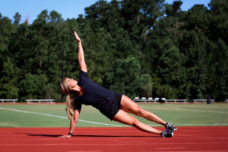 Christie Nix in a side plank on a sports pitch.