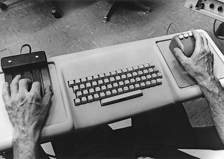 Douglas Engelbart using chord keyset, a standard QWERTY keyboard, and 3-button mouse,