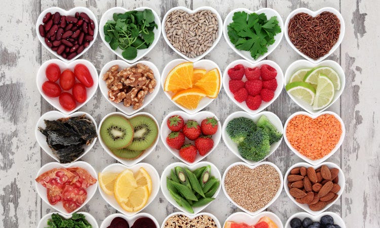 A table with over 20 heart-shaped bowls. Each bowl contains a common recipe ingredients including: tomatoes, almonds, lime slices, and pumpkin seeds.