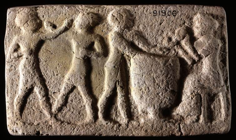 An ancient stone carving shows boxers on the left and drummers on the right.