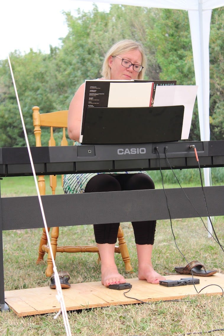 Closeup of woman onstage outdoors seated at electric piano
