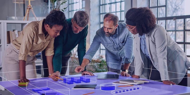 Employees gathering around an office design board.