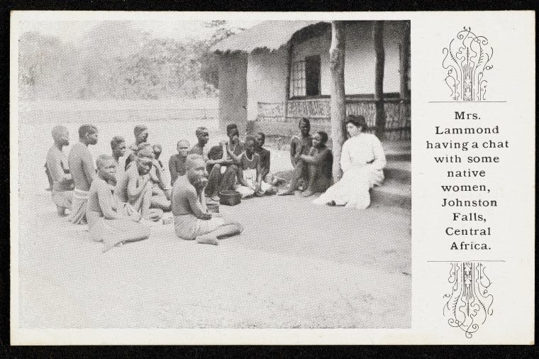 Postcard featuring an image of a white woman in a white dress with a group of black African women in traditional wear, sat outside a building. On the right is the caption ‘Mrs Lammond having a chat with some native women, Johnston Falls, Central Africa’.