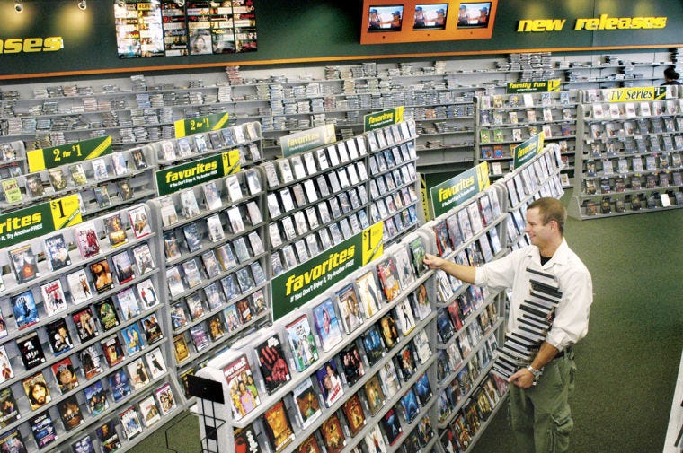 An employee stocks the shelves of a Family Video movie rental store